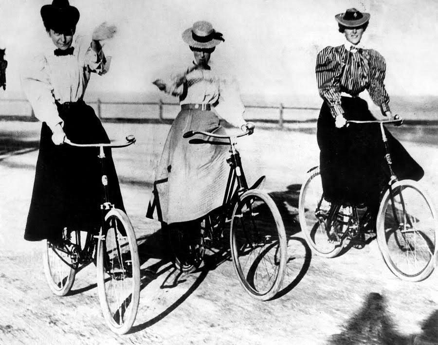 three women riding bicycles on a beach